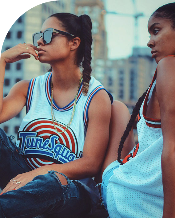 Duas mulheres pousando para foto com regatas de basquete retrôs, vista seu esporte favorito
